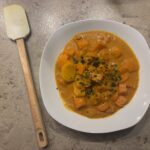 Ein Teller cremiges Blumenkohl‑Curry mit Kokosmilch, Gemüse und frischen Kräutern.