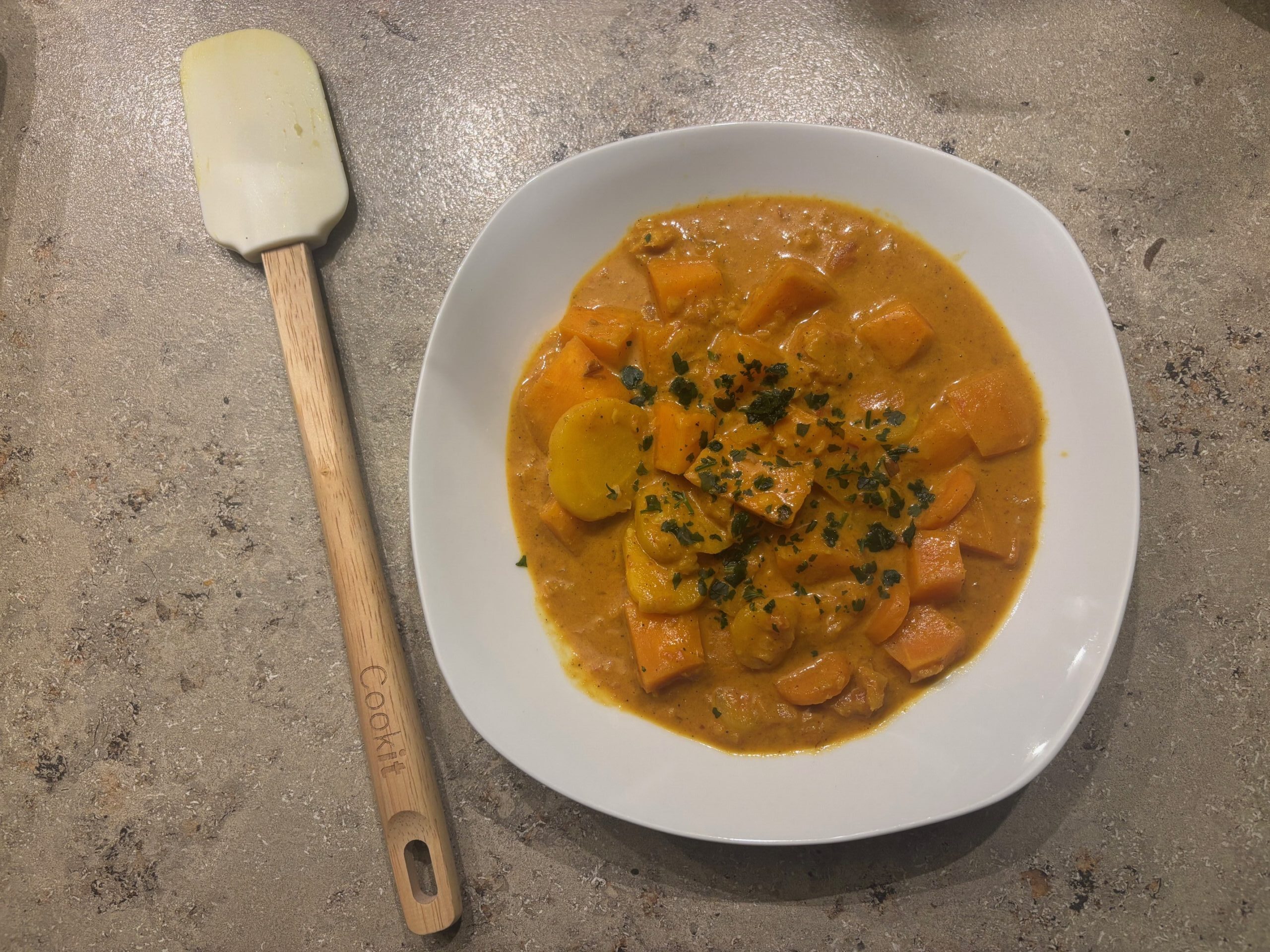 Ein Teller cremiges Blumenkohl‑Curry mit Kokosmilch, Gemüse und frischen Kräutern.