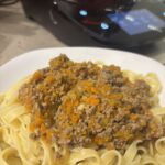 Ein Teller Pasta mit cremiger Bolognese Bianco, verfeinert mit Parmesan und Kräutern.