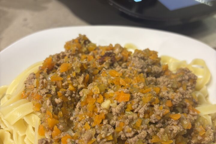 Ein Teller Pasta mit cremiger Bolognese Bianco, verfeinert mit Parmesan und Kräutern.