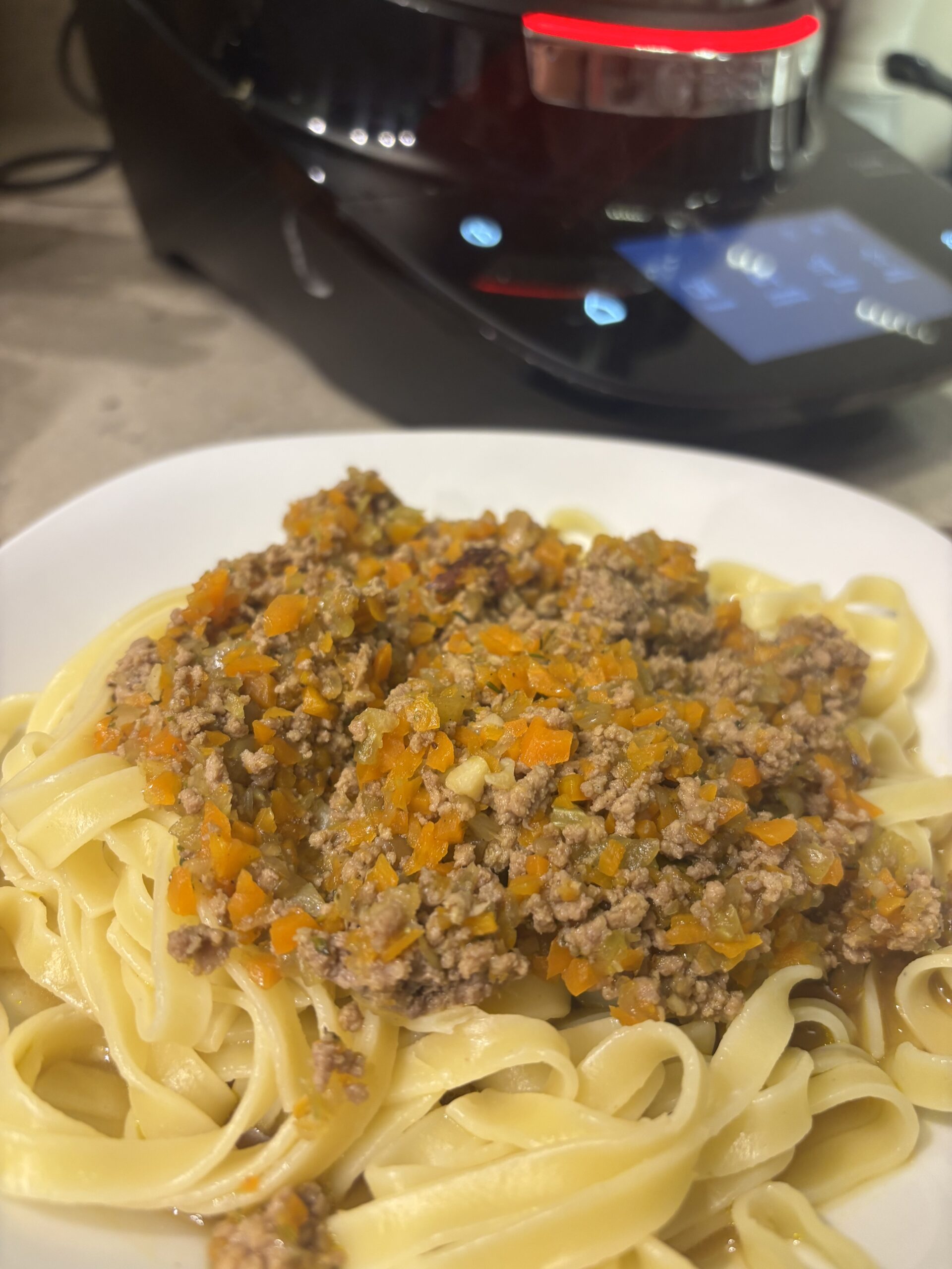 Ein Teller Pasta mit cremiger Bolognese Bianco, verfeinert mit Parmesan und Kräutern.