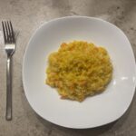 Ein Teller cremiges Kürbis‑Risotto mit leuchtend orangefarbenem Kürbis und Parmesan.