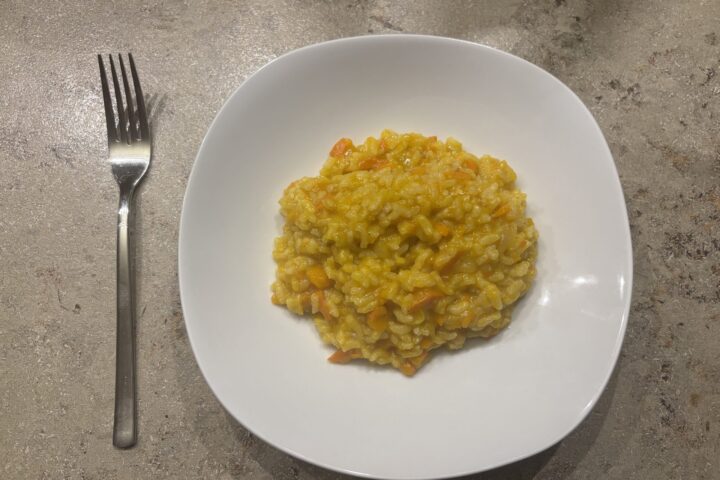 Ein Teller cremiges Kürbis‑Risotto mit leuchtend orangefarbenem Kürbis und Parmesan.