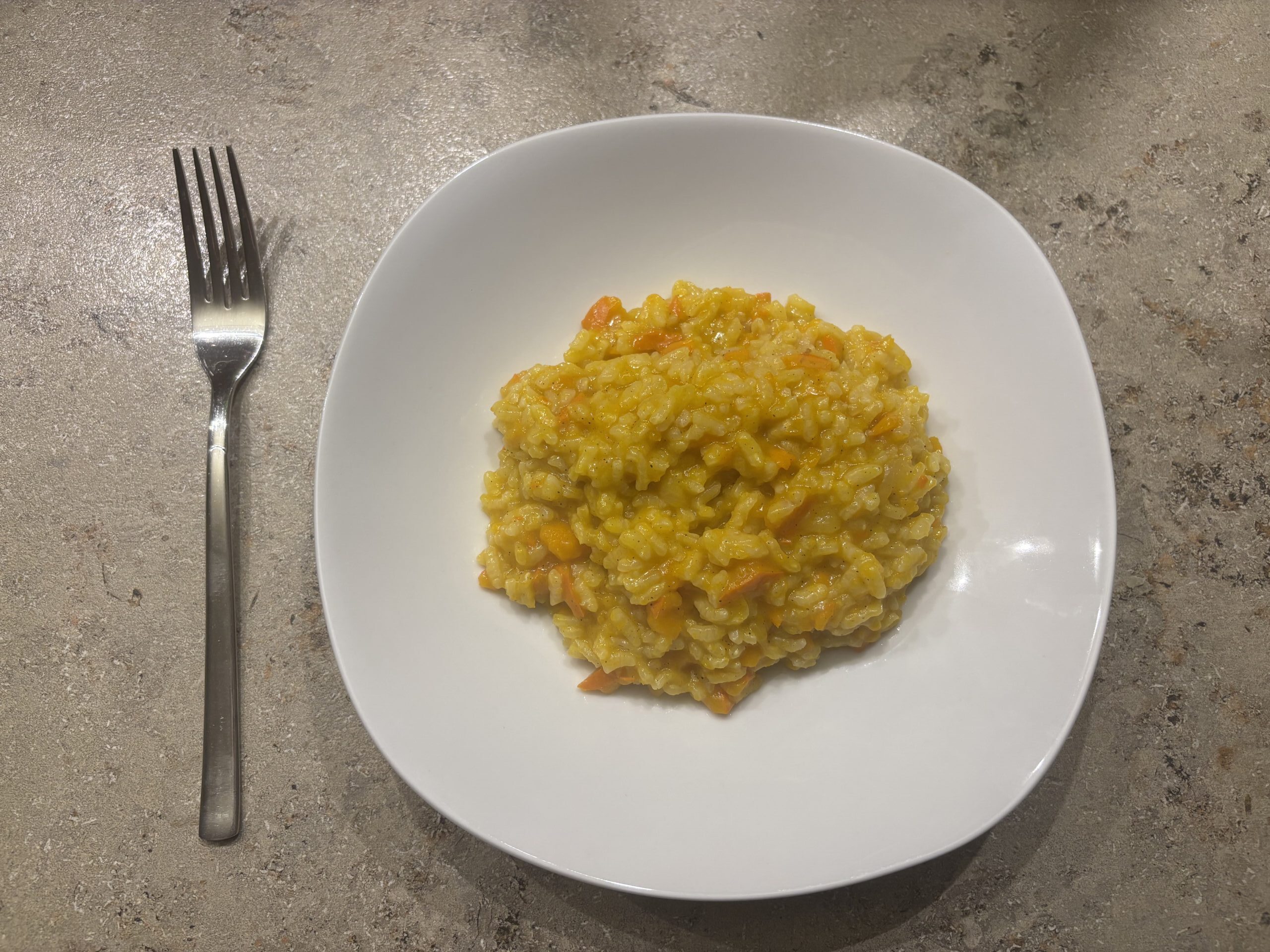 Ein Teller cremiges Kürbis‑Risotto mit leuchtend orangefarbenem Kürbis und Parmesan.
