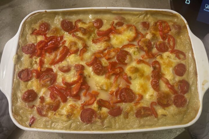 Ein Teller Polenta‑Auflauf mit cremiger Polenta, buntem Gemüse und goldbrauner Oberfläche.