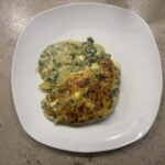 Ein Teller mit cremigem Spinat‑Kartoffel‑Auflauf, serviert mit goldbrauner Kruste und frischem Spinat.